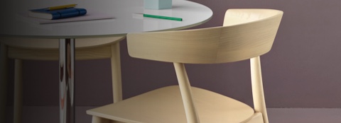 Partial views of three all-wood Leeway side chairs surrounding a  round table with a white top.