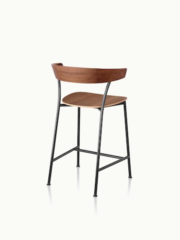 A counter-height Leeway Stool with a metal frame and a wood backrest and seat in a medium finish, viewed from behind at an angle.