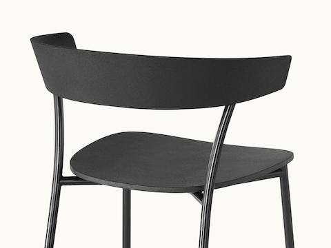 The upper portion of an all-black Leeway Stool, viewed from behind at an angle to show how the back legs support the curved backrest.