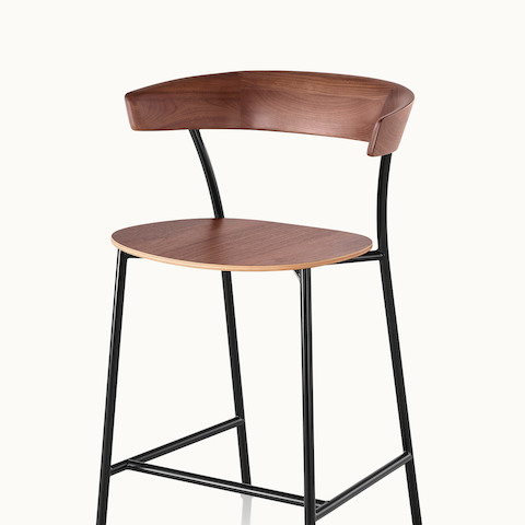 Angled view of a Leeway Stool with a black metal frame and a wood backrest and seat in a medium finish.