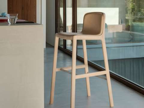 Lijn Stool designed by Carole Baijings for Geiger with leather upholstered seat and back on a matte wood frame viewed at an angle in a styled environment. Lijn Stool designed by Carole Baijings for Geiger with leather upholstered seat and back on a matte wood frame viewed at an angle in a styled environment.