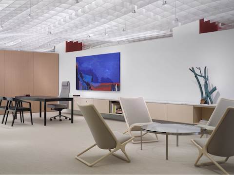 An executive suite featuring a desk in the background and a round Metal Series coffee table surrounded by four beige Scissor Chairs in the foreground.