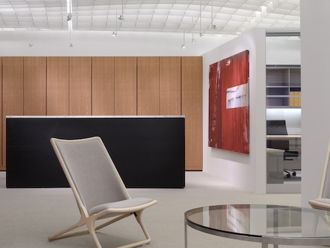 A beige Scissor Chair complements a round Metal Series coffee table in a contemporary reception space.