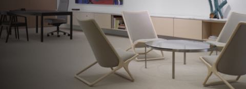 An executive sitting area featuring a round Metal Series coffee table with a glass top surrounded by four beige Scissor Chairs.