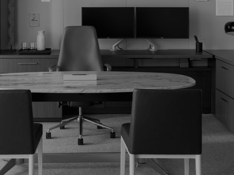 Black-and-white image of an executive office featuring an oval MP Height-Adjustable Table with a stone top used as a desk.