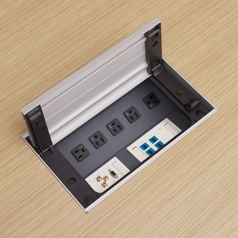 Close-up of a power center built into an MP Table, showing the flip lid open to reveal power, voice, and data connections.
