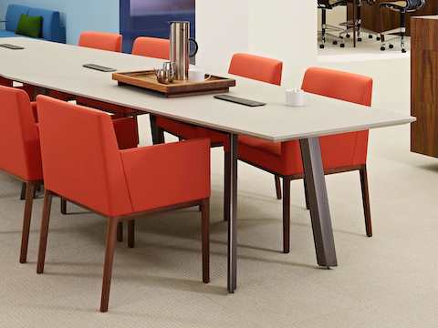 An open meeting area featuring a Geiger Elsi conference table surrounded by red Nessel side chairs.