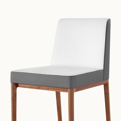 Angled view of an armless Nessel side chair with two-tone upholstery in off-white and gray.