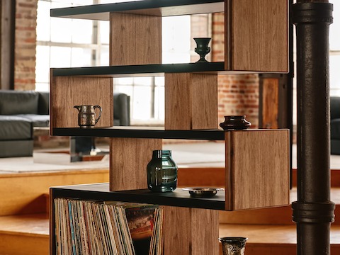 New Canaan High Bookshelf designed by BassamFellows for Geiger in Walnut with Black Leather shown angled in a residential setting with books and objects on shelves.