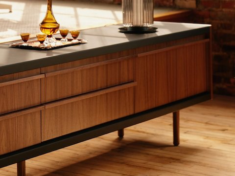New Canaan Media Unit designed by BassamFellows for Geiger in Walnut with Black Leather shown angled in a residential setting.