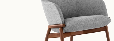 Partial angled view of the middle portion of a Reframe lounge chair with light gray upholstery and a wood frame with a medium finish.