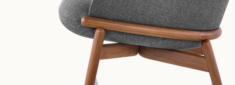 Partial side view of a Reframe lounge chair, showing the wood frame with a medium finish.