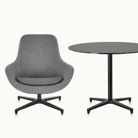 A dark gray Saiba Lounge Chair next to a round Saiba occasional table with a black top and base.