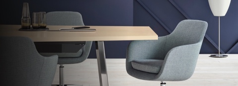 Partial view of a meeting space featuring a conference table and light gray Saiba conference chairs.