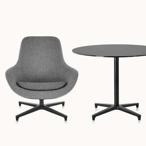A gray Saiba Lounge Chair, viewed from the front, next to a round Saiba occasional table with a black top and base.