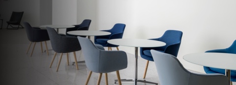 An informal meeting space featuring round Saiba occasional tables with Saiba Side Chairs upholstered in various shades of blue.