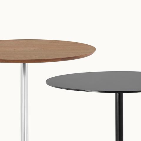 Partial view of two Saiba occasional tables with round tops in veneer and black back-painted glass.
