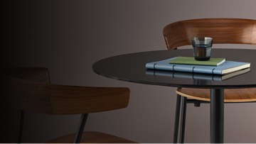 Booklets and a drinking glass on the surface of a round Saiba occasional table with a black back-painted glass top.