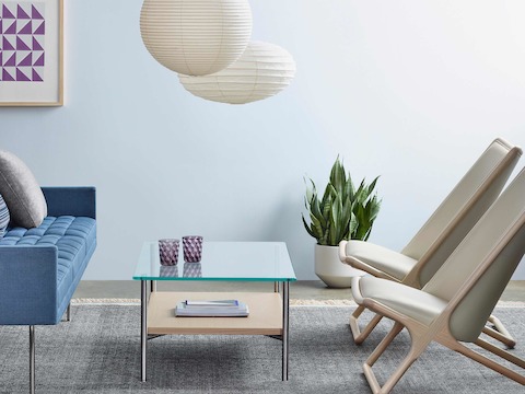 A sitting area featuring two Scissor lounge chairs with ivory-colored leather upholstery, a Layer coffee table, and a blue Tuxedo Component sofa.