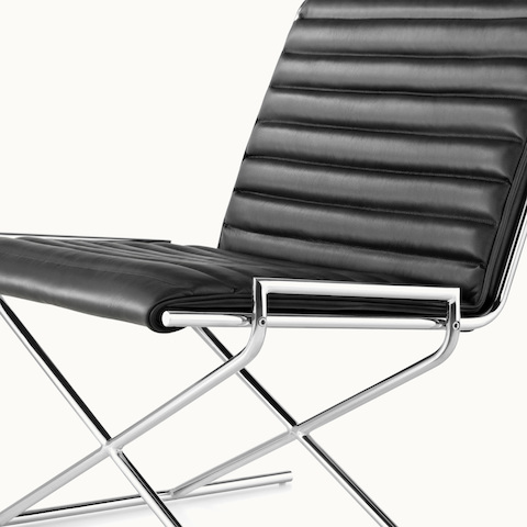 Angled view of a black leather Sled lounge chair, showing the ribbed seat and back.