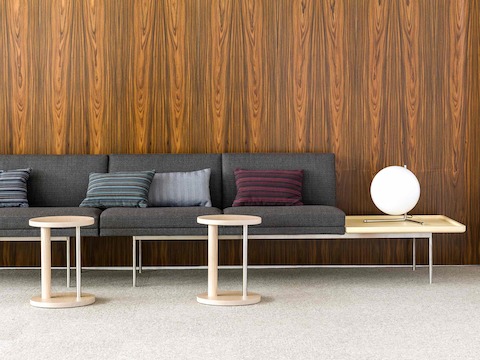 Partial view of a lounge space featuring a dark gray Tuxedo Component settee with an attached table and accent pillows.