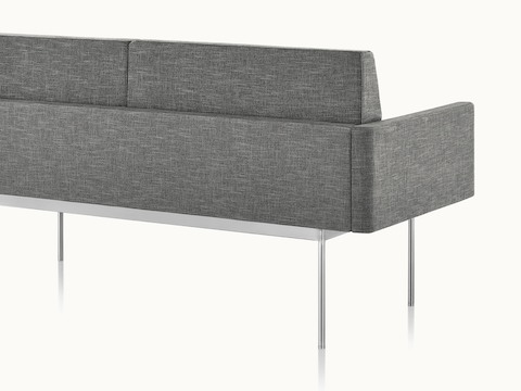 A three seat Tuexdo Sofa featuring a bronze base and gray upholstery, viewed from behind.