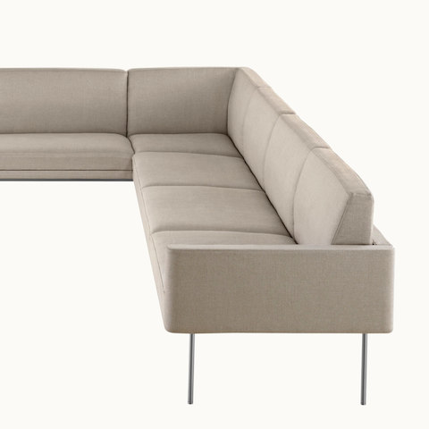 Partial view of a non-quilted Tuxedo Component corner unit upholstered in beige fabric.