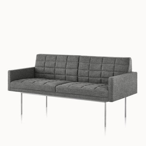 Angled view of a quilted Tuxedo Component settee upholstered in gray fabric. Select to go to the Tuxedo Component Lounge Seating product page.