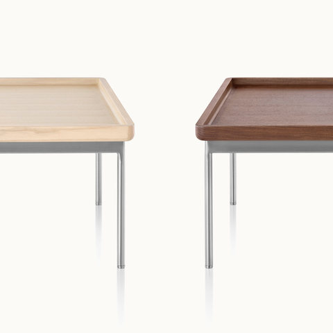 Partial view of two Tuxedo Component occasional tables with steel-plated legs, one with a light wood top and the other with a medium wood top.
