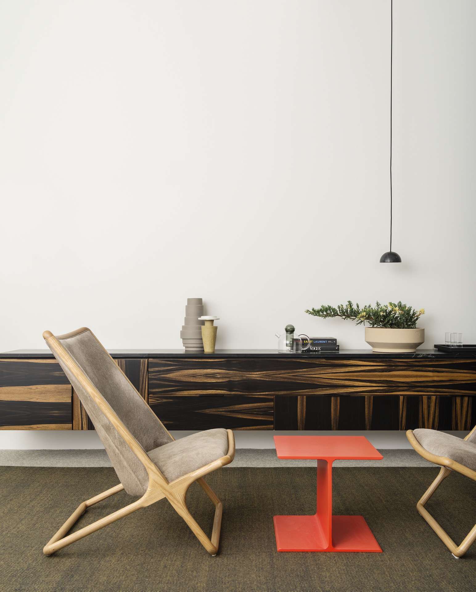 An intimate meeting space with two wood-frame Scissor Lounge Chairs in Maharam tuft thunder textile and a red I-Beam side table.