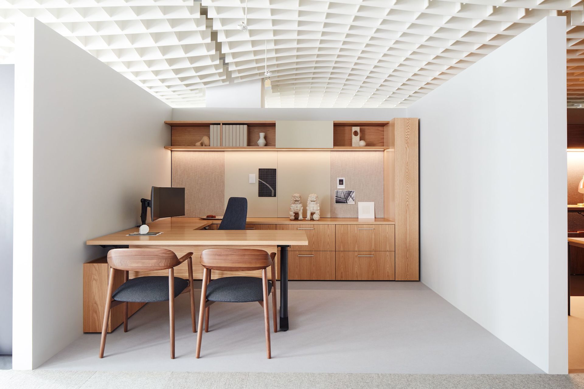 A private office vignette in the Geiger showroom, featuring Geiger One Casegoods with matte sand backpainted glass, a Taper Chair, and Crosshatch Side Chairs.