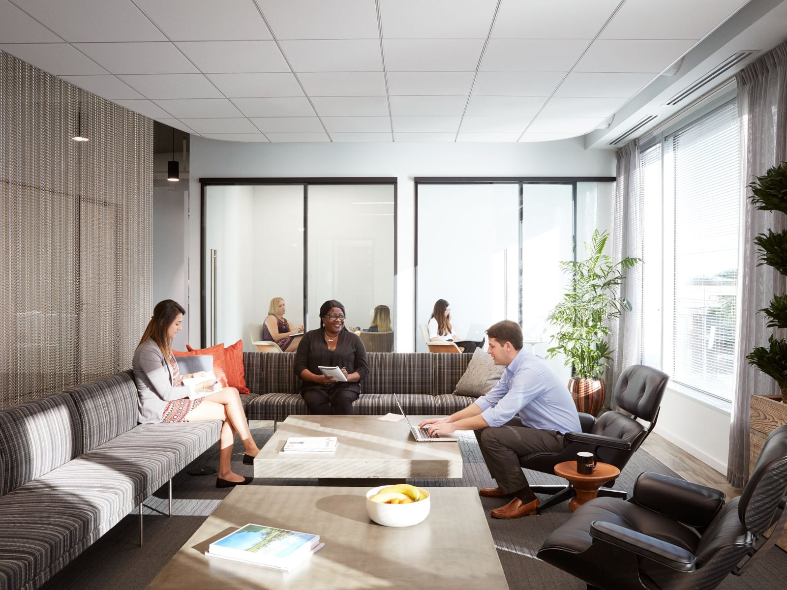 Three people sit in a lounge area with reclined chairs and couches.