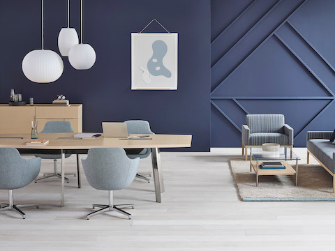 A meeting space featuring a conference table with gray Saiba Chairs adjacent to a sitting area furnished with Wood Base Lounge Seating and a Layer Table.