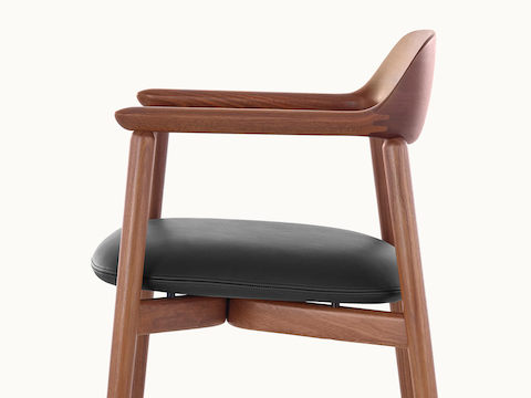 Side view of a Crosshatch Side Chair with a medium wood finish and black leather seat pad, showing the meticulous craftsmanship.